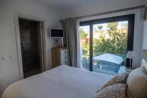 a bedroom with a bed and a large window at The Beach House Roof in Vila Nova de Cacela