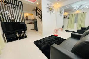 Shiella's Staycation House Cabanatuan في كاباناتوان: غرفة معيشة مع أريكة وتلفزيون بشاشة مسطحة