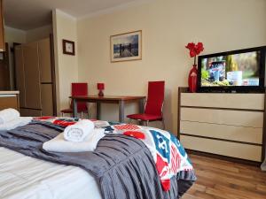 a bedroom with a bed with towels and a tv at Apartament TRZY POMOSTY Villa Mistral in Świnoujście