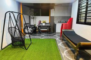 Shiella's Staycation House Cabanatuan في كاباناتوان: غرفة مع أرجوحة وسجادة خضراء
