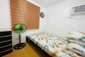 Shiella's Staycation House Cabanatuan في كاباناتوان: غرفة نوم بسرير ومروحة