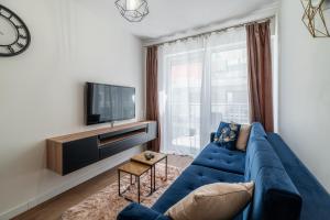 a living room with a blue couch and a tv at Horyzont Apartamenty - Kapitański Mostek- BLISKO PORTU- Śniadania in Kołobrzeg