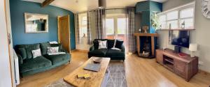 sala de estar con sofá verde y TV en The Lodge@Tyddyn Ucha en Caernarfon
