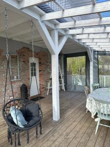 eine Veranda mit einer Schaukel und einem Tisch auf einer Terrasse in der Unterkunft DEJA VU in Kretinga