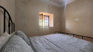 Schlafzimmer mit einem Bett und einem Fenster in der Unterkunft Escapade famille - vue panoramique et piscine privée in Aït Ghemat