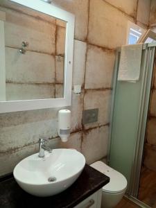a bathroom with a sink and a toilet and a mirror at Port Hotel, Tasucu in Silifke