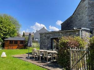 a patio with a table and chairs and an umbrella at Les Lavandes de Durbuy in Durbuy