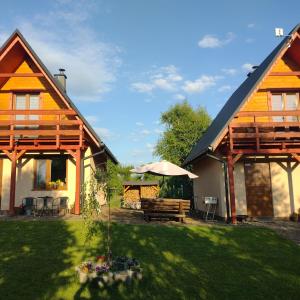 une maison avec une cour dotée d'un banc et d'un parasol dans l'établissement Domki Brzozówka w Bieszczadach, à Ustrzyki Dolne