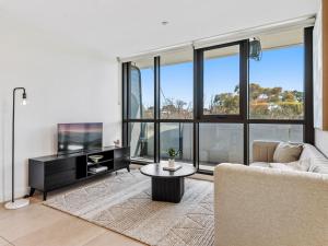 a living room with a couch and a tv at Light Filled Apartment by Albert Park & Lake in Melbourne