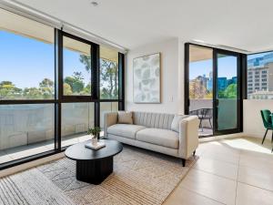 ein Wohnzimmer mit einem Sofa und einem Tisch in der Unterkunft Light Filled Apartment by Albert Park & Lake in Melbourne