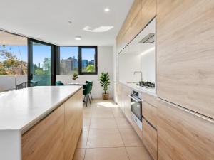 a kitchen with white countertops and wooden cabinets at Light Filled Apartment by Albert Park & Lake in Melbourne