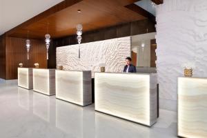 a man standing behind a counter in a lobby at Marriott Executive Apartments Al Jaddaf, Dubai in Dubai
