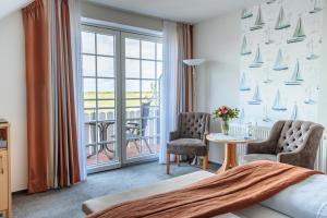 ein Hotelzimmer mit einem Bett und Stühlen sowie einem Balkon in der Unterkunft Hotel Schiffer in Bensersiel