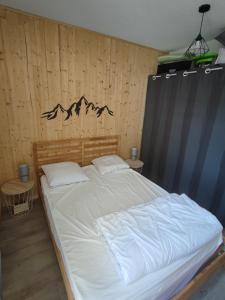 a bedroom with a large bed with a wooden wall at Appartement avec belle vue sur montagne in Égat