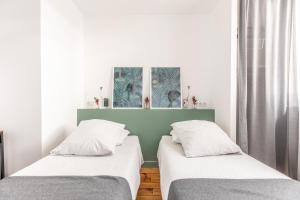 twee bedden in een kamer met witte muren en ramen bij La maison de Vallières in Clermont-Ferrand