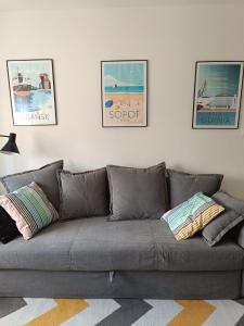 eine graue Couch in einem Wohnzimmer mit Bildern an der Wand in der Unterkunft Sopot Green 65 in Sopot