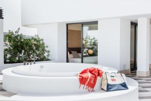 a white bath tub in a bathroom with shopping bags at El Hotel Pacha in Ibiza Town