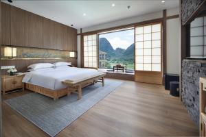 a bedroom with a large bed and a large window at The Giggling Tree in Yangshuo