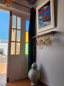 a door to a room with a vase and a painting at Dar Adul in Essaouira