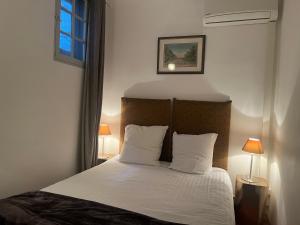 a bedroom with a bed with white sheets and pillows at Duplex Face au Palais in Avignon