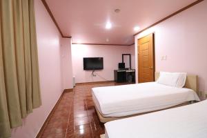 une chambre d'hôtel avec deux lits et une télévision dans l'établissement Busan Station Centum Hotel, à Busan