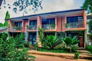 una casa rosa con balcones y árboles frente a ella en PRIMESHADE GUESTHOUSE en Malindi