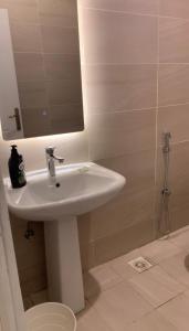 uma casa de banho com um lavatório branco e um chuveiro em فيلا رسن em Al Hada