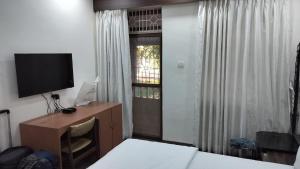 a bedroom with a desk with a television and a window at Gracias Villa in Panaji