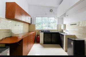 a kitchen with wooden cabinets and a sink and a window at Gracias Villa in Panaji