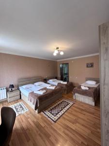three beds in a room with wooden floors at Kazbegi Guide in Kazbegi