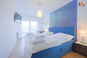 sypialnia z niebieskim łóżkiem z białą pościelą i poduszkami w obiekcie MS Pro Apartamenty AQUARIUS w Kołobrzegu