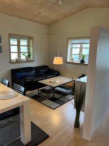 - un salon avec un canapé noir et une table dans l'établissement Skøn lejlighed til 4 personer, à Ansager