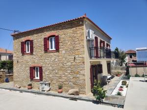 a stone house with red shutters on a building at Lucy's luxury II in Néa Koútali