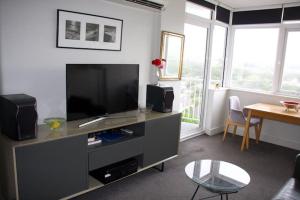 uma sala de estar com uma televisão de ecrã plano e uma mesa em Seaside Serenity - Stunning Beach Views in Maroubra em Sidney