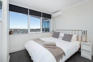 a white bedroom with a large bed and large windows at Seaside Serenity - Stunning Beach Views in Maroubra in Sydney
