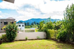 un giardino con recinzione e alcune piante e montagne di Fijian Homestay - 3 bedroom house a Nadi