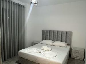 a bedroom with a bed with a gray headboard at Mehmeti Apartment in Sarandë