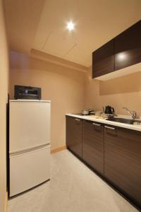 a kitchen with a white refrigerator and a sink at UNWIND Hotel & Bar Sapporo in Sapporo
