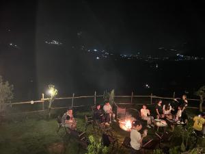 Un groupe de gens assis autour d'un feu la nuit dans l'établissement Pavi garden, à Sa Pa