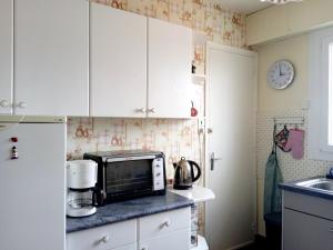 une cuisine avec des placards blancs et un four micro-ondes sur un comptoir dans l'établissement Les pieds dans l'eau, à Saint-Hilaire-de-Riez