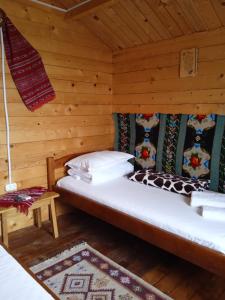 a bedroom with a bed in a log cabin at Căsuțele dintre vii in Runcu