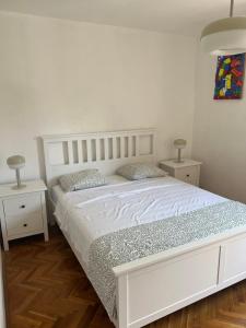 a bedroom with a white bed with two night stands at Art Apartment Mali Losinj in Mali Lošinj