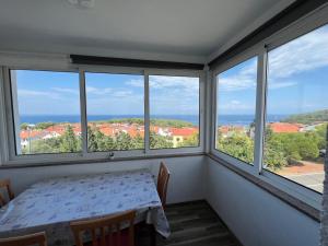 a dining room with a table and four windows at Art Apartment Mali Losinj in Mali Lošinj