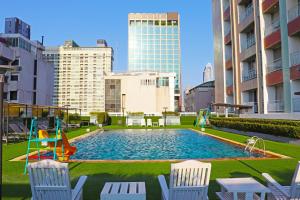 a pool with chairs and a playground in a city at Evergreen Place Siam by UHG in Bangkok