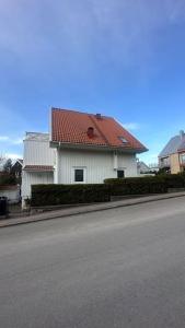 a white house with a red roof on a street at Superhomes 1 BR in Gothenburg