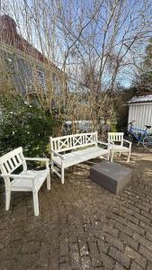 three white benches sitting on a brick patio at Superhomes 1 BR in Gothenburg