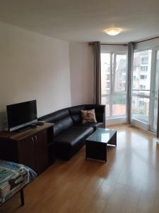 a living room with a black leather couch and a tv at Sea Garden Burgas in Burgas City +7 photos