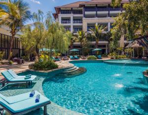 uma piscina num hotel com cadeiras e um edifício em Royal Tulip Springhill Resort Jimbaran em Jimbaran