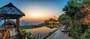 Pu LuongにあるPu Luong Eco Gardenのプールと夕日を望むリゾートの景色を望めます。