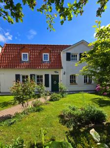 une maison blanche avec un toit rouge et une cour dans l'établissement Haus mit 110qm und Garten 150m zum Wasser, à Stralsund